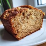 Close-up of a moist slice of cottage cheese banana bread showing a golden-brown crust and soft crumb.