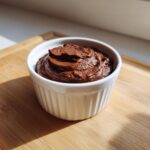 A single serving of rich, dark brown cottage cheese chocolate mousse piped into a white ramekin.
