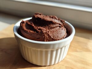 A serving of rich, dark chocolate mousse made with cottage cheese in a white ramekin.