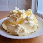 A generous mound of incredibly creamy, yellow-tinted mashed potatoes recipe served on a white plate.