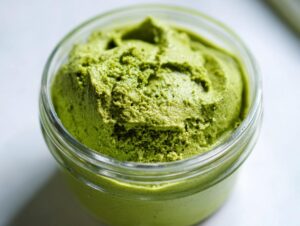 Close-up of thick, vibrant green matcha chia pudding served in a small glass jar.