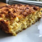 Close-up of a slice of baked squash casserole with a crispy, browned top crust.