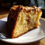 Close-up of a moist slice of jewish apple cake showing its golden crumb and apple chunks.