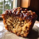 Close-up cross-section of a pecan pie muffin showing the moist crumb and sticky pecan topping.