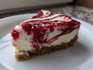 A close-up of a perfect slice of creamy raspberry cheesecake with a graham cracker crust.