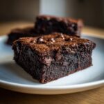 Close-up of a fudgy, dark chocolate vegan brownies square with a shiny top.