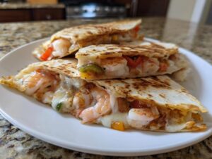 Close-up of three slices of a golden-brown shrimp quesadilla filled with melted cheese, shrimp, and peppers.