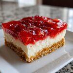 Close-up of a square slice of strawberry pretzel salad showing a pretzel crust, cream cheese layer, and strawberry topping.