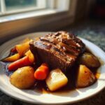 A close-up of a thick slice of tender pot roast served with carrots and potatoes in rich gravy.