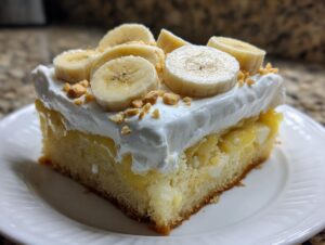 A moist slice of banana pudding poke cake topped with whipped cream, fresh banana slices, and crushed wafers.