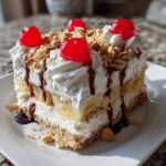 A decadent slice of banana split cake featuring layers of crust, bananas, whipped cream, and topped with cherries and nuts.