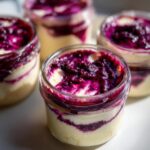 Close-up of a berry swirl high protein cheesecake jar showing creamy filling and vibrant purple berry topping.