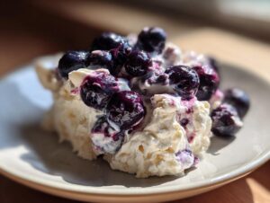 Close-up of a scoop of creamy blueberry fluff salad topped with fresh, glistening blueberries.
