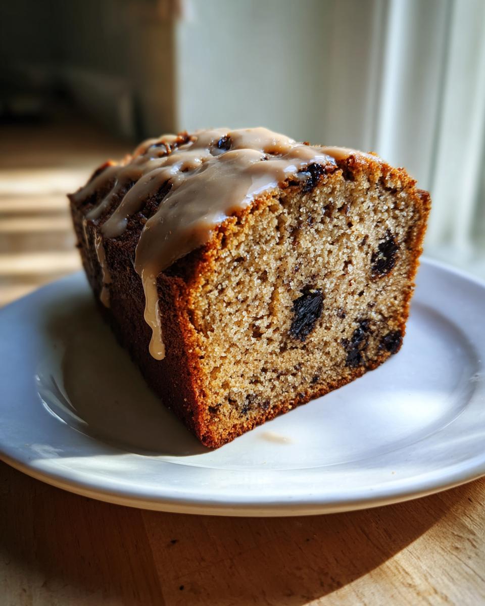 A close-up of a moist slice of cardamom date cake topped with a thick, dripping caramel glaze.
