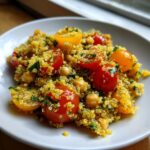 Close-up of a bright chickpea quinoa salad featuring yellow quinoa, chickpeas, and halved red and yellow cherry tomatoes.