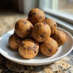 A stack of homemade chocolate chip protein balls piled high on a small white dish.