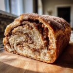 A close-up cross-section of a freshly baked loaf of cinnamon sugar bread showing rich swirls of filling.
