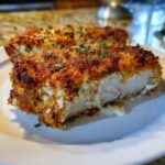 Close-up of a thick slice of copycat Longhorn Steakhouse Parmesan Chicken with a golden-brown, crispy crust.