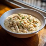 A close-up of creamy white chicken chili recipe featuring shredded chicken and white beans, garnished with parsley.