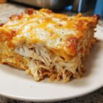 A close-up view of a hearty slice of fajita chicken casserole topped with melted, bubbly cheddar and Monterey Jack cheese.