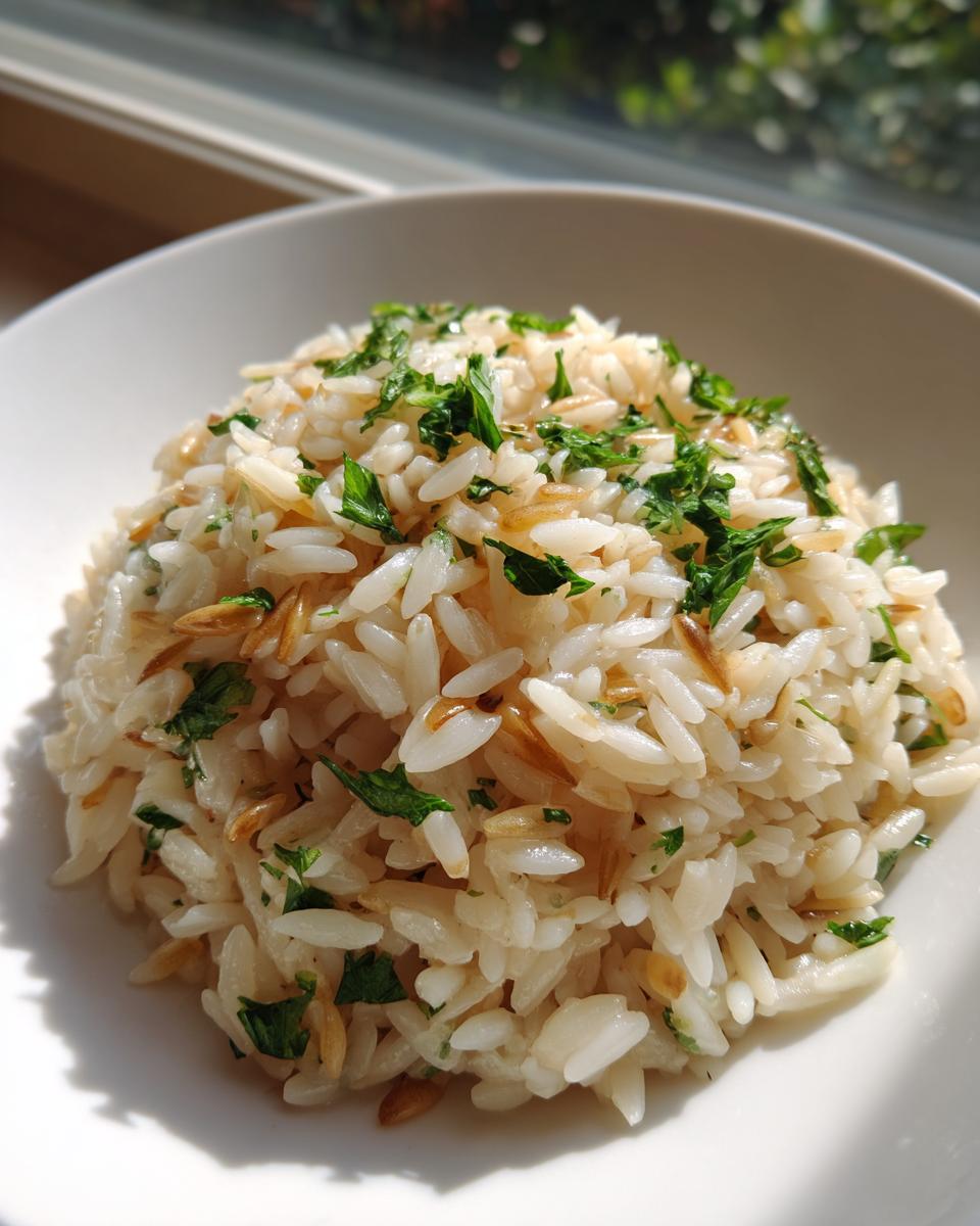 Close-up of fluffy rice pilaf mixed with toasted vermicelli and topped with fresh chopped parsley.