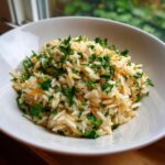 Close-up of fluffy rice pilaf mixed with orzo and topped generously with chopped fresh parsley.