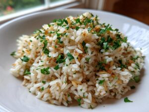 Close-up of fluffy white rice pilaf garnished generously with chopped fresh parsley and crispy toasted bits.