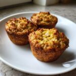 Three golden-brown baked banana oatmeal cups resting on a white plate.
