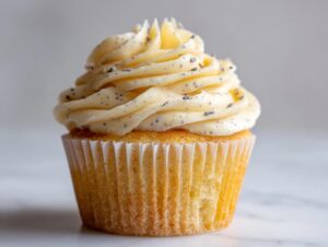 A single, beautifully frosted lavender honey cupcake featuring pale yellow frosting speckled with lavender buds.