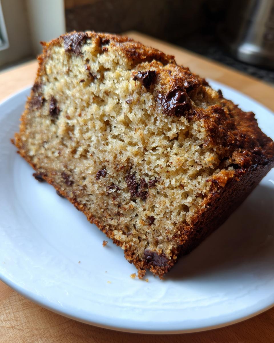 Close-up of a moist slice of chocolate chip protein banana bread on a white plate.