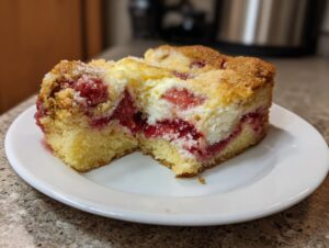 Close-up of two squares of strawberry cheesecake dump cake showing layers of cake, cream cheese, and strawberry filling.