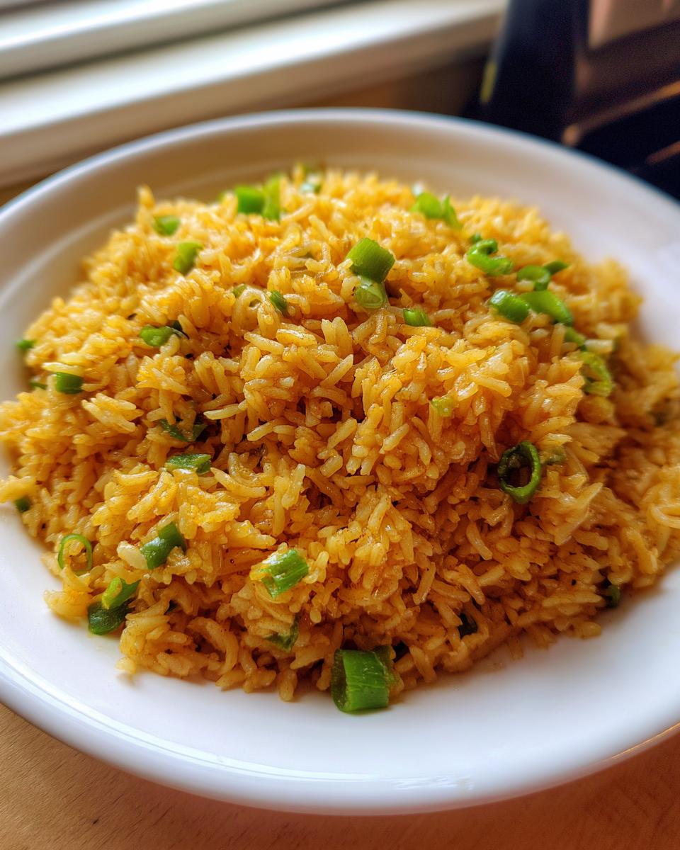 A close-up shot of a white bowl filled with golden brown texas roadhouse seasoned rice, topped with chopped green onions.