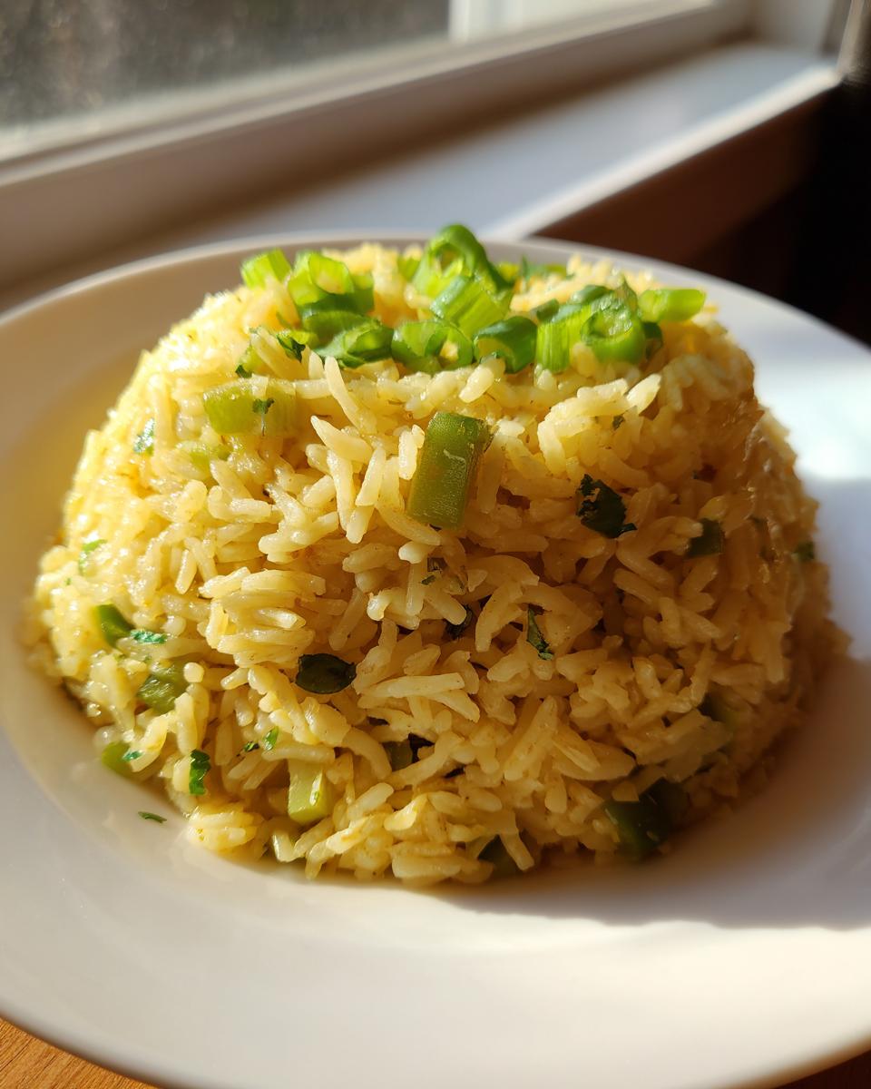 A perfectly molded serving of yellow Texas Roadhouse seasoned rice topped with fresh green onions.