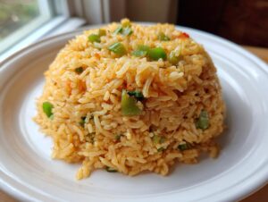 A perfectly molded serving of flavorful texas roadhouse seasoned rice topped with green peppers on a white plate.
