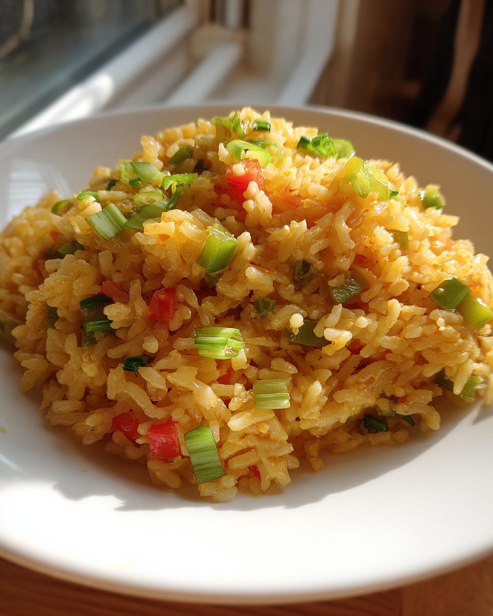 A close-up of a mound of golden texas roadhouse seasoned rice topped with diced green onions and red peppers.