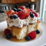 A thick slice of moist tres leches pancakes soaked in milk, topped with whipped cream and fresh mixed berries.