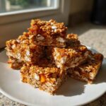 A stack of chewy tropical mango flapjacks delight bars loaded with oats and coconut flakes on a white plate.