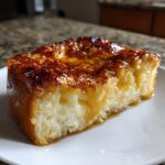 A thick slice of Crème brûlée French toast with a caramelized, crackly sugar top served on a white plate.