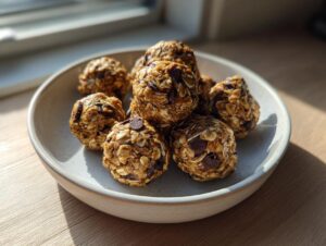 A stack of homemade Peanut Butter Oatmeal Energy Bites mixed with visible chocolate chips, served in a light ceramic bowl.