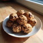A mound of homemade Peanut Butter Oatmeal Energy Bites studded with chocolate chips on a light plate.