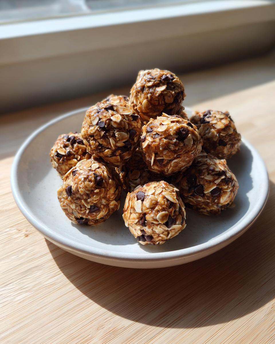 A stack of homemade Peanut Butter Oatmeal Energy Bites studded with chocolate chips, resting on a small white plate.