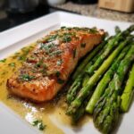 A perfectly cooked fillet of Sheet pan garlic butter salmon served with bright green asparagus spears and rich butter sauce.